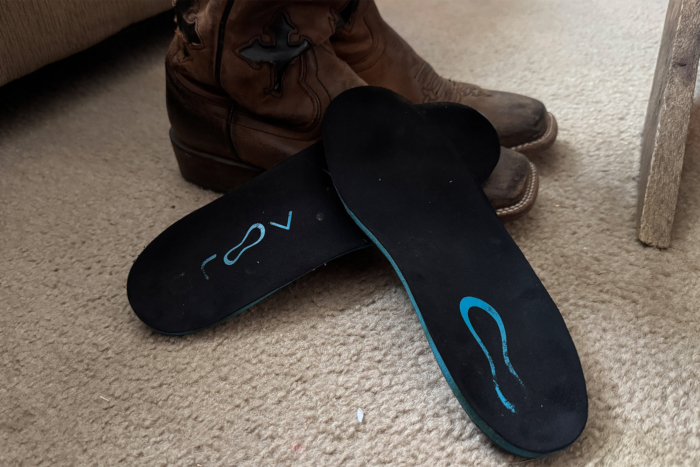 Groov custom insoles placed on carpet beside a pair of boots
