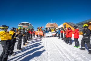 lines of ski patrollers and employees lined up below chairlift off-ramp on opening day 2026