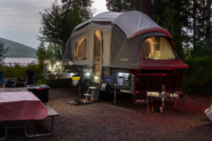 Opus OP4 LE illuminated at a lakeside campsite with the outdoor kitchen open