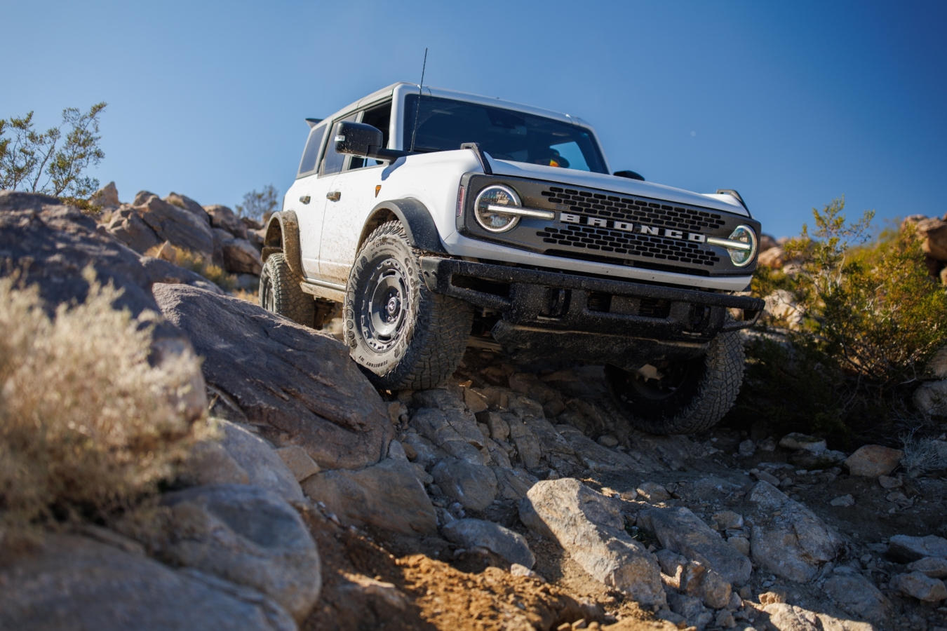 White Ford Bronco crawls over rocks in the desert