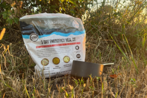 Roundhouse Provisions emergency meal kit and saucepan set outdoors in dry grass
