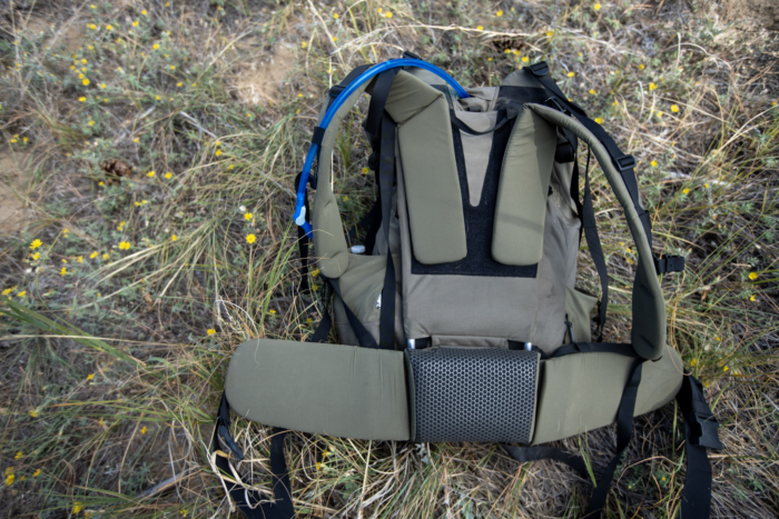 The shoulder strap adjustment system of a hunting backpack that is laying on the ground.