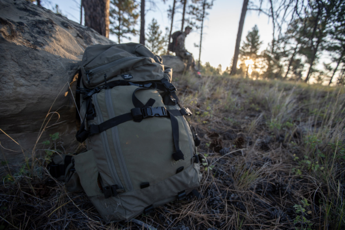 The Kings Camo XKG Summit 5200 Backpack leaned against a rock in the mountains as the sun rises on the horizon.