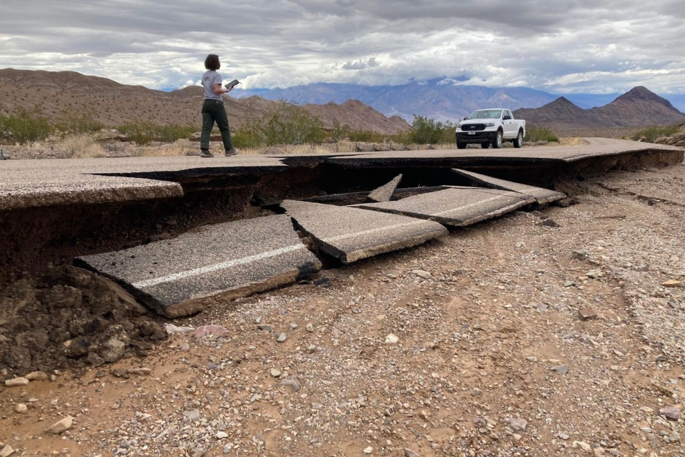 person walks along damaged road