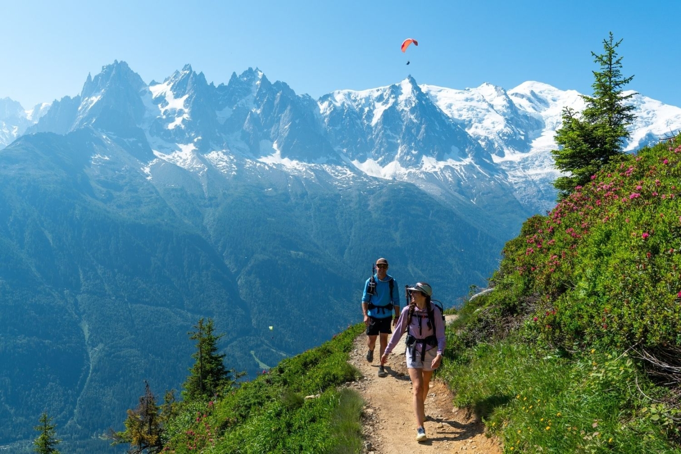 two hikers on trail with mountains in background