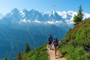 two hikers on trail with mountains in background