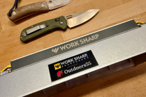 Bench sharpener on a work surface with two folding knives