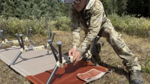man setting up a cot wearing kuiu attack pants