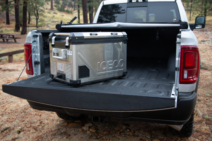 A stainless steel electric cooler sits in the bed of a pickup truck