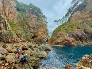 hikers scrambling over a rocky inlet