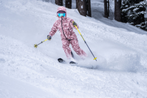 woman skiing downhill with hood on