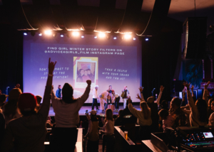 crowd in a movie theater standing and cheering shot from behind