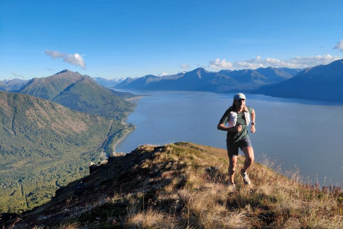 Trail runner wearing the Terignota Valhalla vest on a mountain ridge overlooking a lake