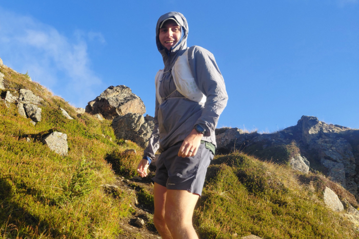 Front view of a white running vest worn over a gray hooded jacket