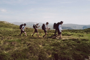 group of four people backpack across field