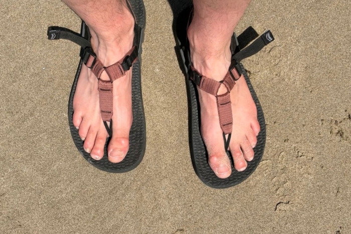 up close shot of person wearing sandals on beach