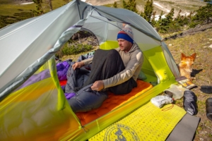 person sitting in tent with sleeping bag liner