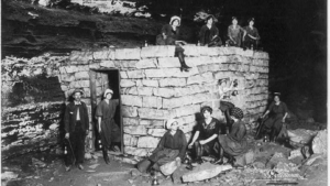 black and white archival image of patients sitting on a crude brick structure in Mammoth Cave