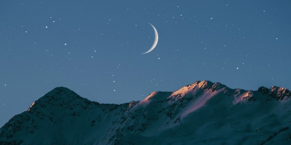 crescent moon over mountains