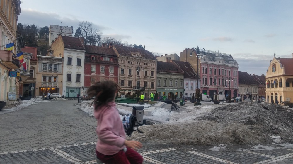 Child unicycles across a snowy town square