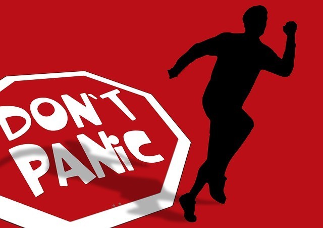 A sign saying 'don't panic' and a man seen running away