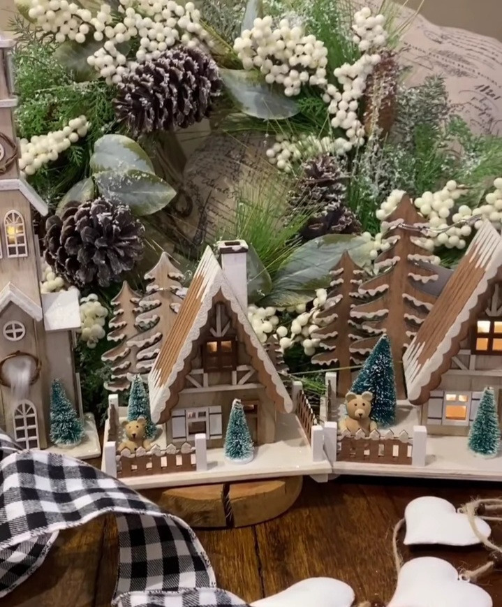 Miniature toy houses covered in snow and decorated with Christmas lights, trees, and pinecones to create the perfect holiday display Miniature toy houses covered in snow and decorated with Christmas lights, trees, and pinecones to create the perfect holiday display
