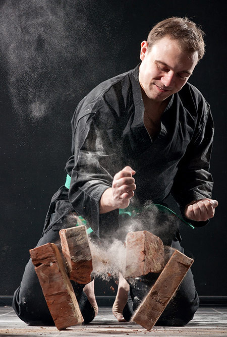 A Man Smashing a Pile of Bricks With His Bare Hands