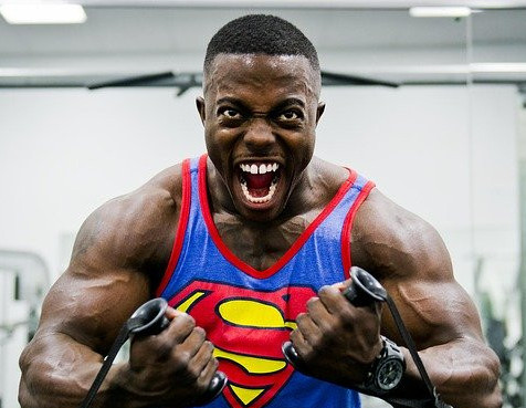 A man wearing a Superman vest tensing his upper body muscles whilst mid-exercise A man wearing a Superman vest tensing his upper body muscles whilst mid-exercise