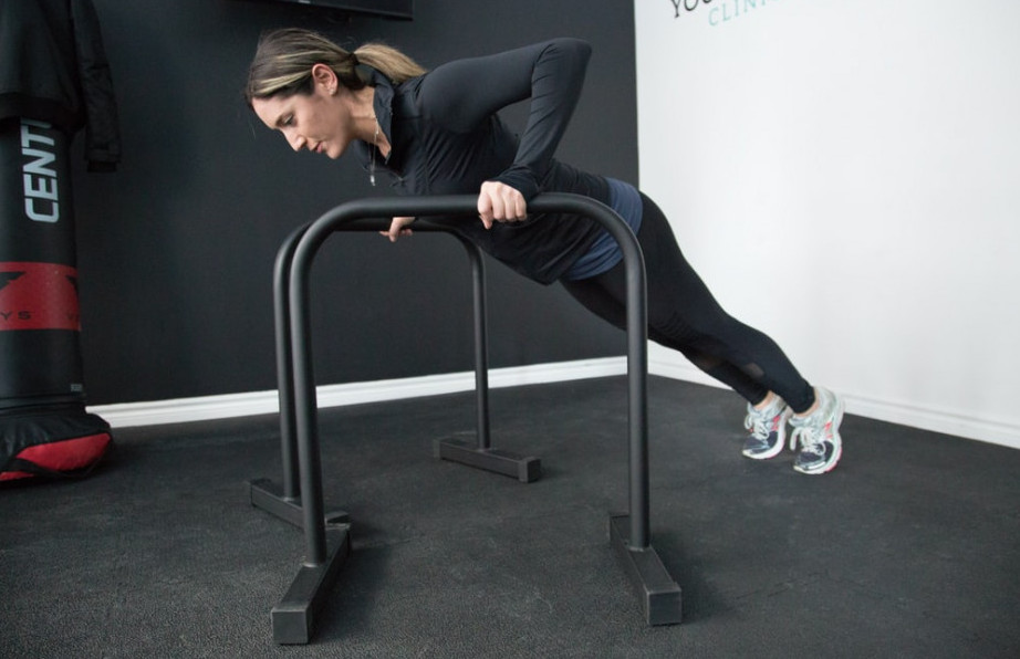 A-woman-performing-an-incline-push-up-with-two-parallel-bars A-woman-performing-an-incline-push-up-with-two-parallel-bars