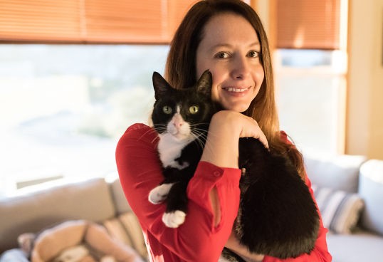 Woman holding cat in her home