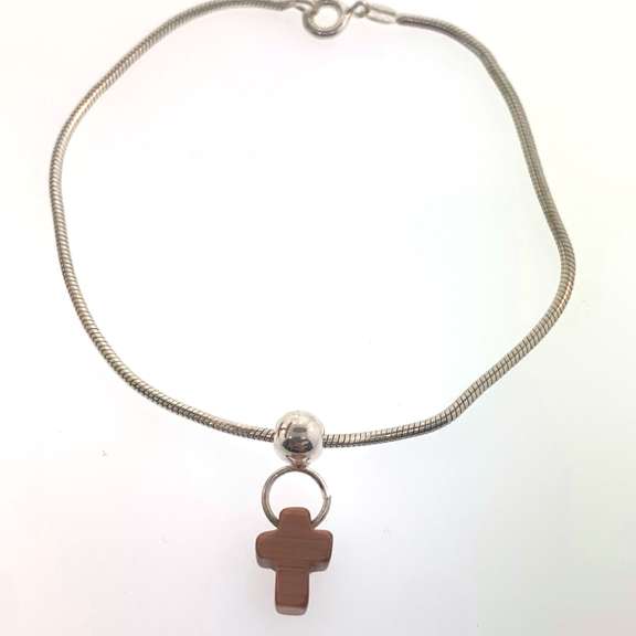 Sterling silver bracelet with one silver bead and an orangish/brown cross charm