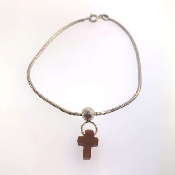 Sterling silver bracelet with one silver bead and an orangish/brown cross charm