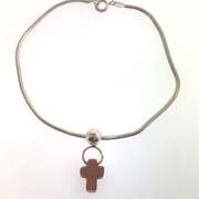 Sterling silver bracelet with one silver bead and an orangish/brown cross charm