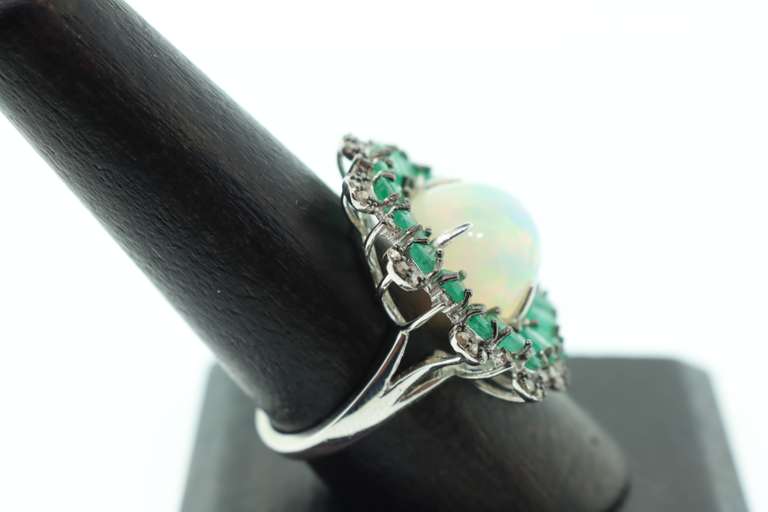 Mesmerizing Opal Ring surrounded by Emeralds and Diamond Accents