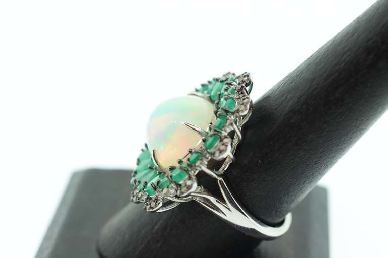 Mesmerizing Opal Ring surrounded by Emeralds and Diamond Accents