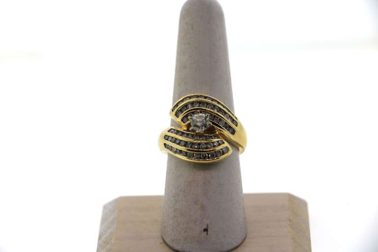 Phenominal Round Diamond Centerpiece clutched by triple row Channel Set Diamonds on a 14k Gold Band