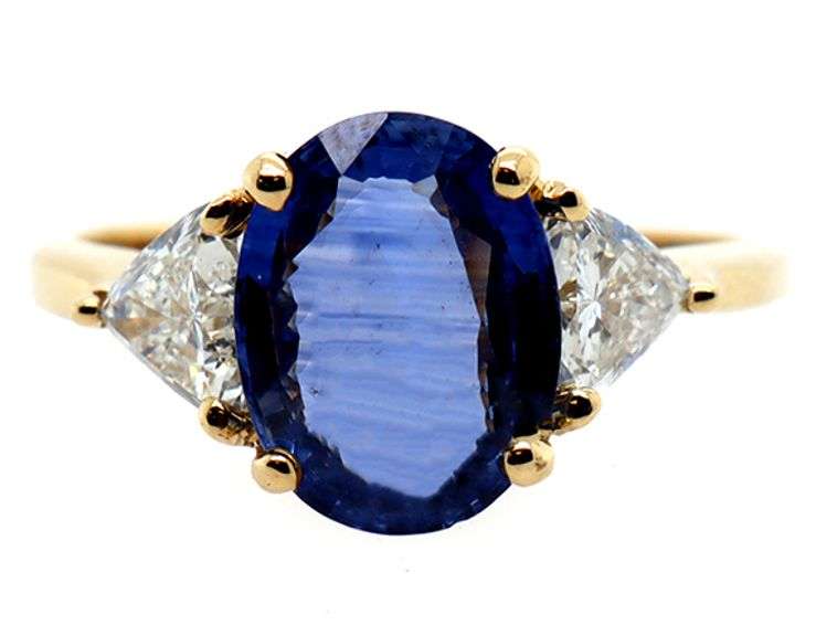 3.50ct Oval Sapphire and 0.80ctw Trillion Cut Diamond Three Stone Ring in 18K Yellow Gold