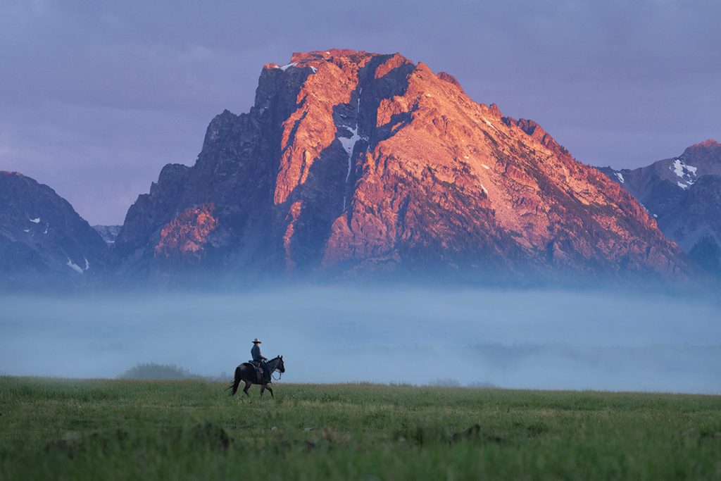A Michael Paul photo of a cowboy riding in the Grand Tetons.
