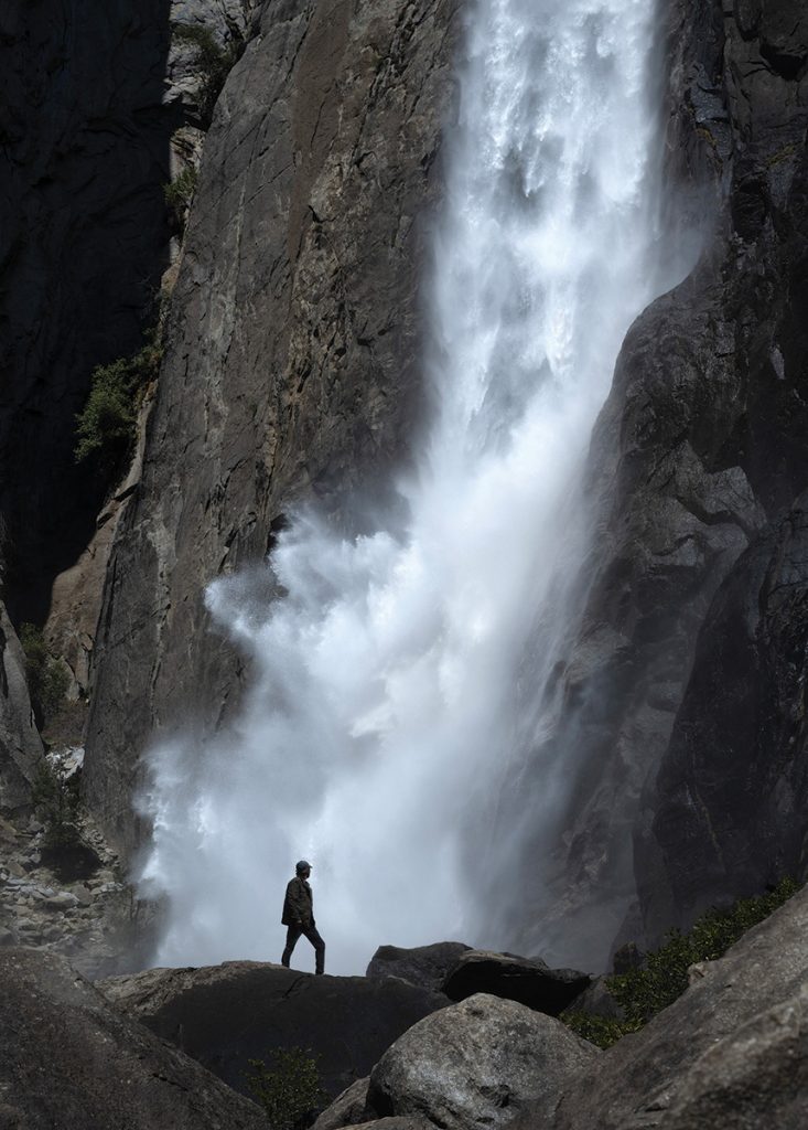 A hiker standing near a waterfall.