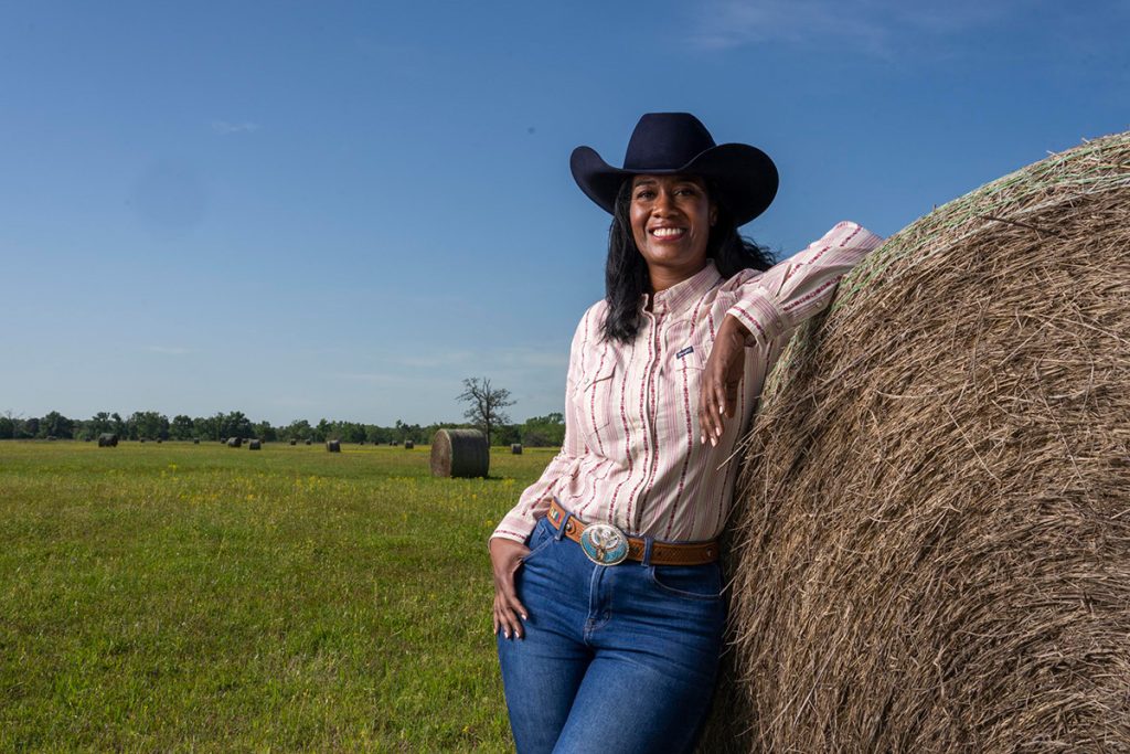 A portrait of the rancher and businesswoman next to a hay bale.