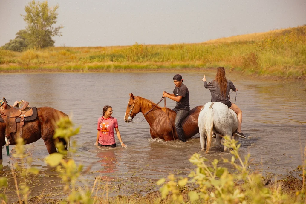 Kids riding their horses in the water.