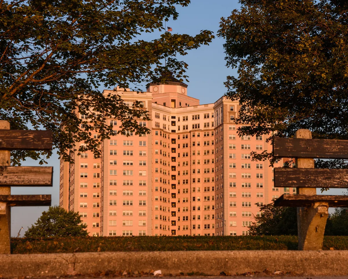 Pink Edgewater Beach Apartments co-op at 5555 N Sheridan Rd in Chicago's Edgewater, framed by trees at sunrise