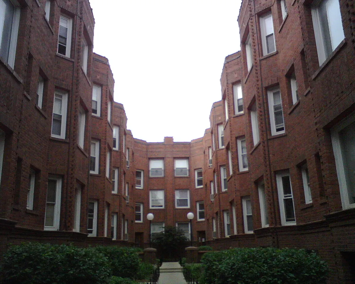 Three-story vintage brick courtyard apartment building with a garden walkway in Chicago's Edgewater