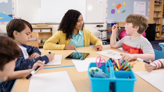 Teacher sitting with a group of students at classroom table