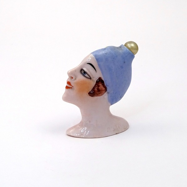Flacone in porcellana a forma di testa di donna. Fiaschetta con testa di Fasold & Stauch, mod. 8530. Il tappo realizzato con una perla è probabilmente una sostituzione successiva, in origine aveva un tappo a corona.  Germania, 1920 ca 6 cm