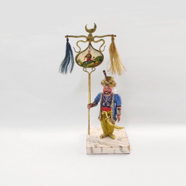 Soldato ottomano di piombo con flacone in vetro come zaino Soldato di piombo dipinto a mano con dettagli e costumi colorati, su una base di legno dipinta per sembrare marmo. Al posto dello zaino porta sulle spalle un piccolo flacone in cristallo. Il supporto del flacone è fatto con sottili fasce d'oro. Il labaro è dipinto su un medaglione di madreperla e mostra un soldato morto, in uniforme europea, ucciso da un soldato ottomano.  Ottoman Empire, 1760 ca   fl. 2 cm