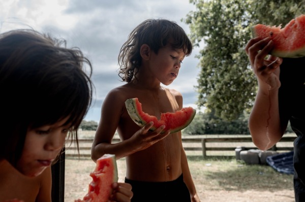 Teepa children share a watermelon. John Rangikapua Teepa and his wife Carol have raised more than 20 children adopted according to the Māori whāngai custom, to strengthen traditions and family ties. Ruatoki, New Zealand, 27 January 2022