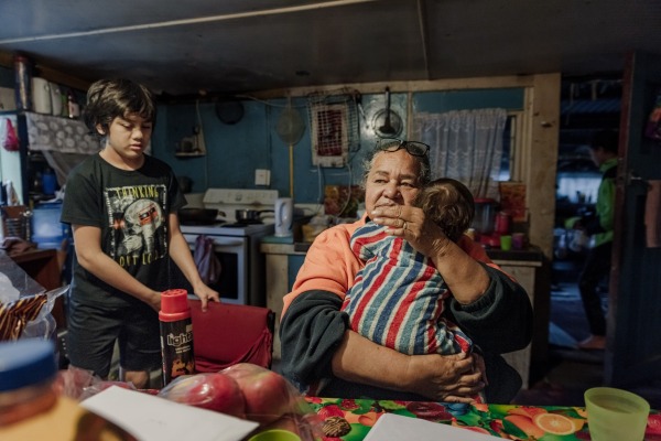 Carol Teepa sits in her kitchen with her youngest grandchild, Mia, and her son, Wanea, one of more than 20 children she adopted according to Māori custom, to strengthen traditions and family ties. Ruatoki, New Zealand, 2 September 2017