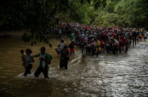 Thousands of migrants wade into the Rio Muerto (“Death River”) at the Darién Gap, where several have drowned in its treacherous waters. They assist one another to prevent drowning in the swift currents. Rio Muerto, Colombia, 2 August 2023