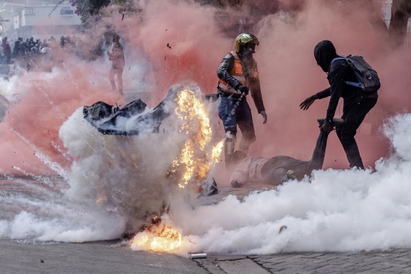 Two protestors helping injured people are hit with tear gas outside the Kenyan Parliament during a national strike against the Finance Bill 2024. Nairobi, Kenya, 25 June 2024